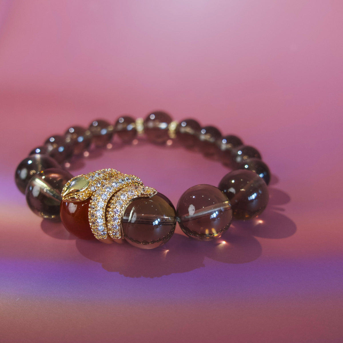 Close-up of smoky quartz, red agate and gold snake charm